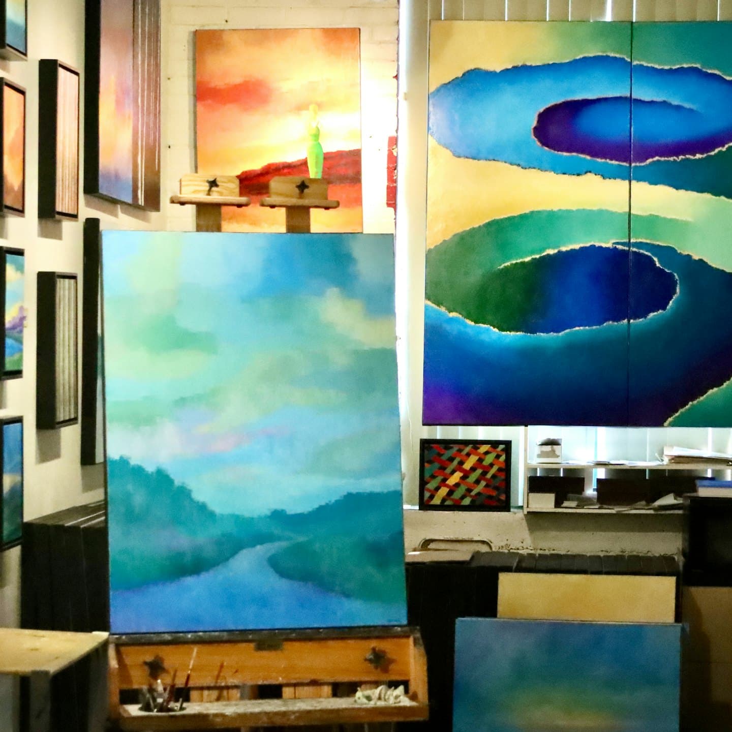 Gemälde an Wänden und Staffeleien in einem Künstleratelier.